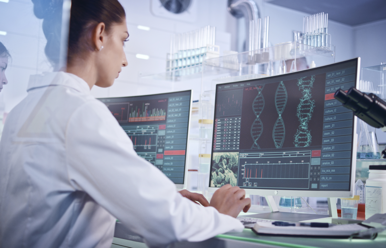 Healthcare professional at a computer showing strands of DNA.